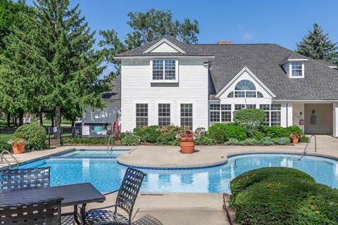a swimming pool with chairs and a house in the background
