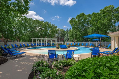 a resort style pool with blue chairs and umbrellas
