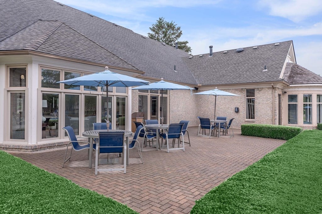 a patio with tables and umbrellas outside of a house