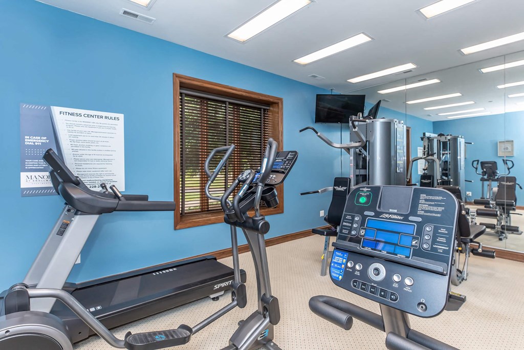 a gym with exercise equipment and a tv in the corner