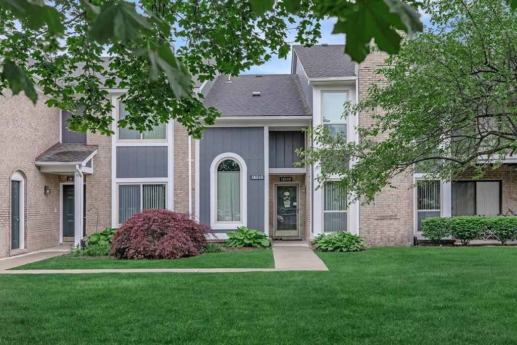 front view of a home with green grass and trees