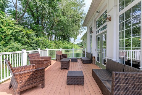 a covered porch with wicker furniture and a large window