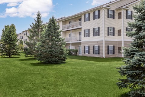 A large grassy area in front of a building with trees.
