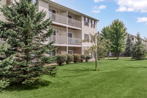 A grassy area in front of a building with balconies.