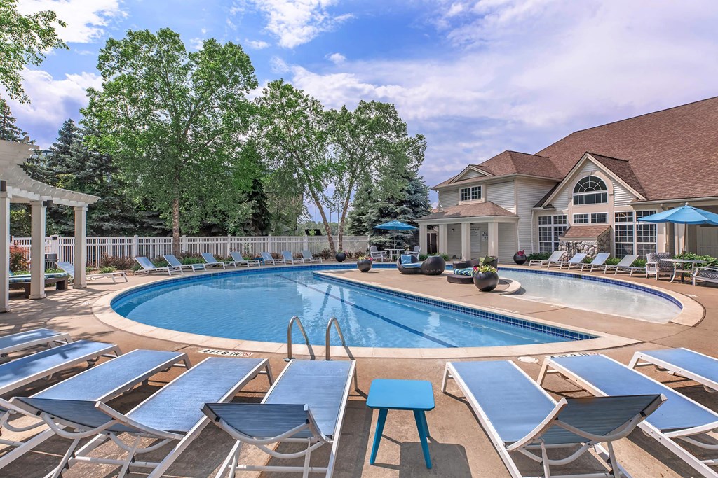 a swimming pool with lounge chairs around it and a house in the background