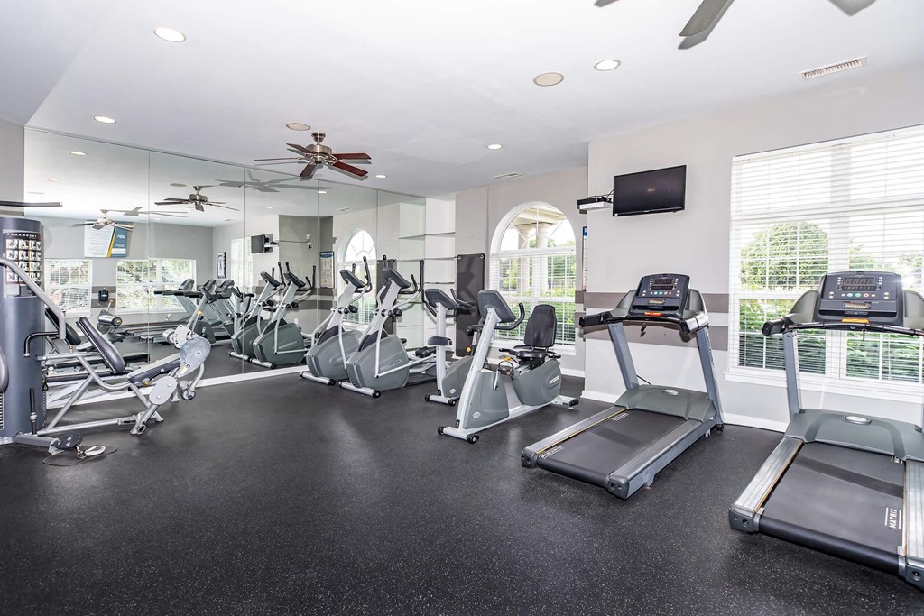 a gym with cardio equipment and windows