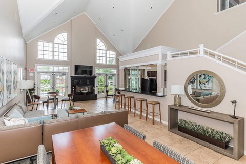 A large, well-lit living room with a fireplace and a long wooden table.