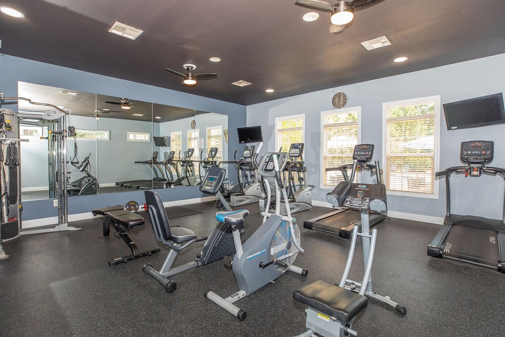 a gym with cardio machines and other exercise equipments and windows