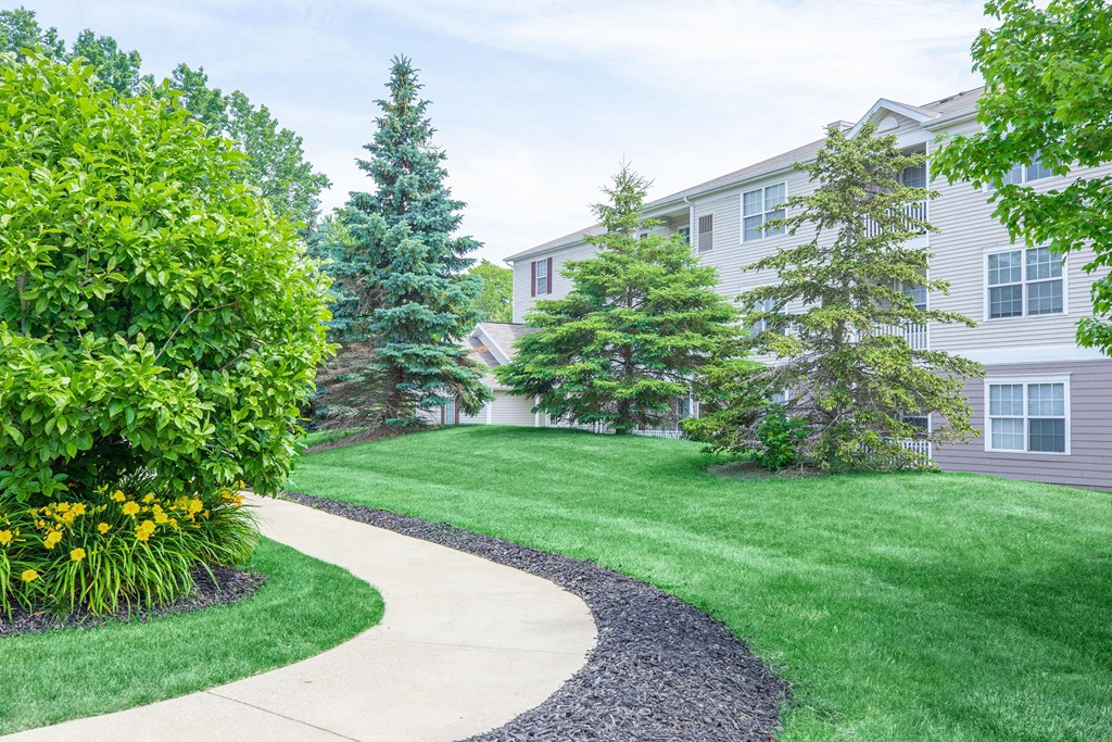 a walkway through the grass in front of a building