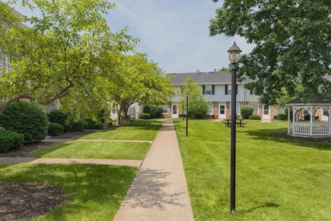 A tree-lined walkway leads to a building.