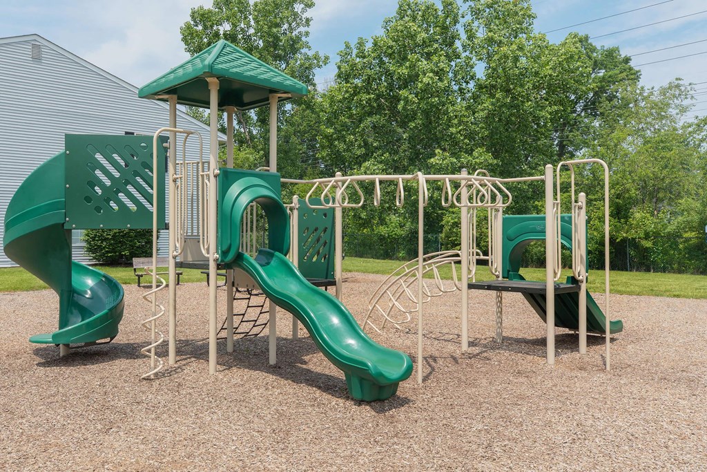 A playground with a green slide and a green roofed structure.