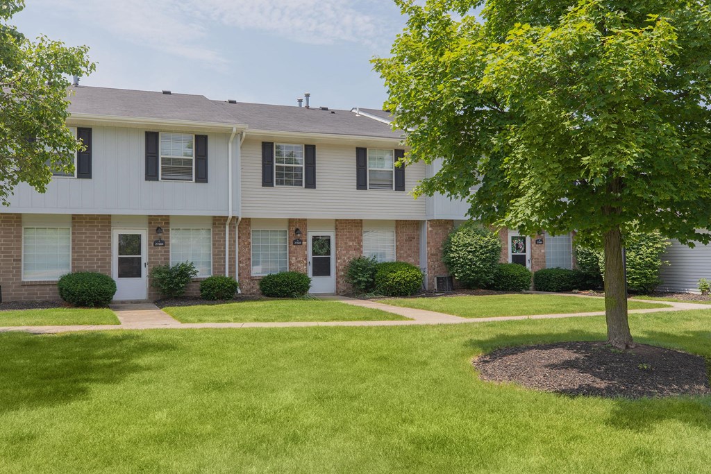 A tree is planted in a circle of dirt in front of a house.