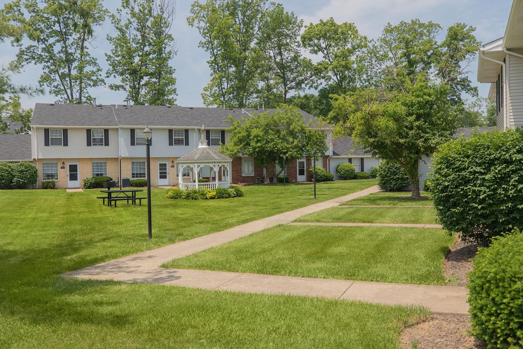 A white and yellow building with a black bench in front of it.