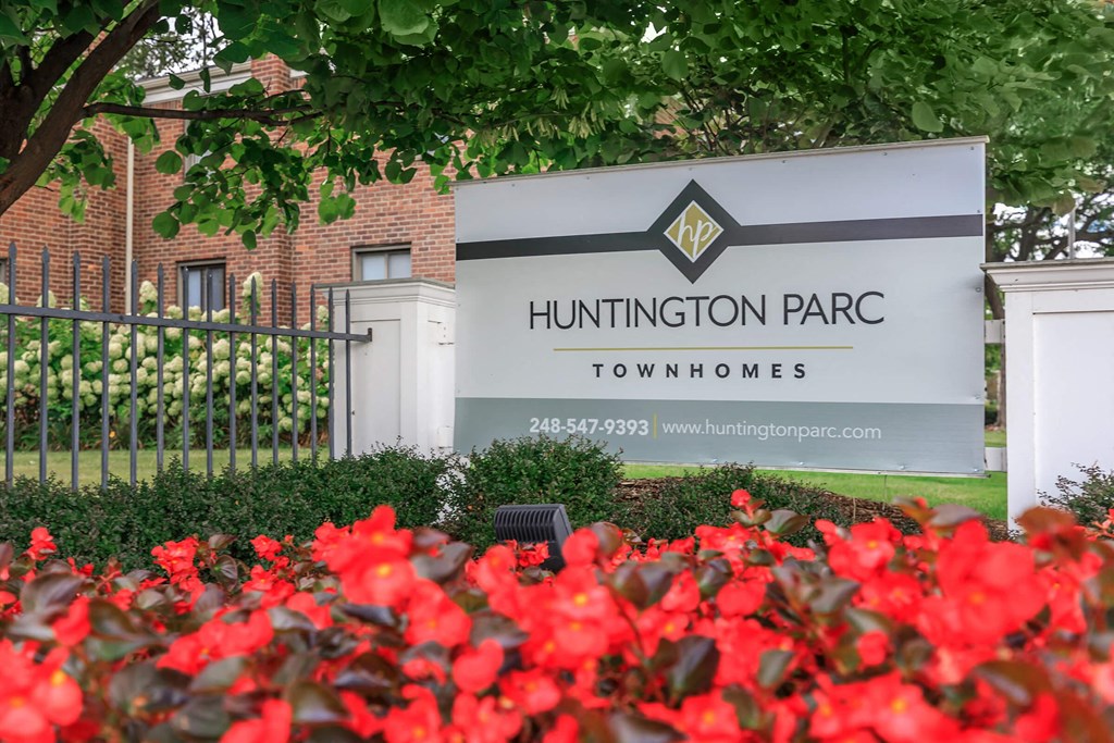 a sign in front of a building with red flowers