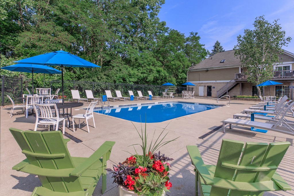 a swimming pool with chairs and umbrellas and a house