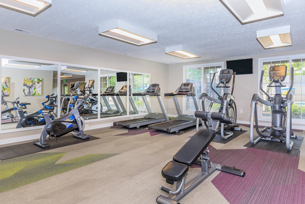 a gym with various exercise machines and windows