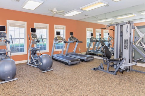 A gym with orange walls and a variety of exercise equipment.