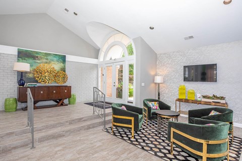 A living room with a green and gold chair and a black and white rug.
