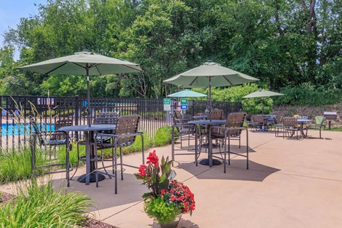 a patio with tables and umbrellas next to a swimming pool