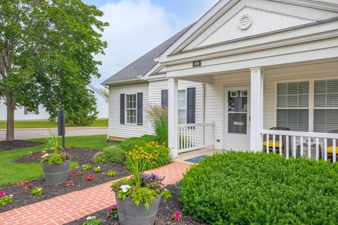 a front porch of a white house with plants and flowers