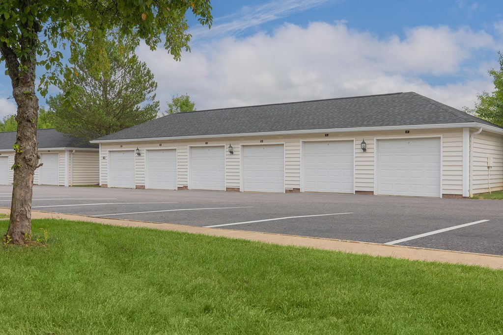 a white building with white roller shutter doors and a parking lot