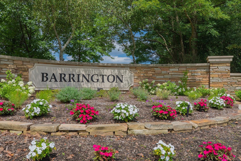 a sign for barrington on a brick wall with flowers