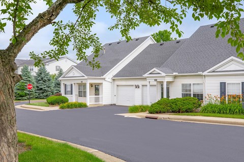 a street in front of a white house with a stop sign