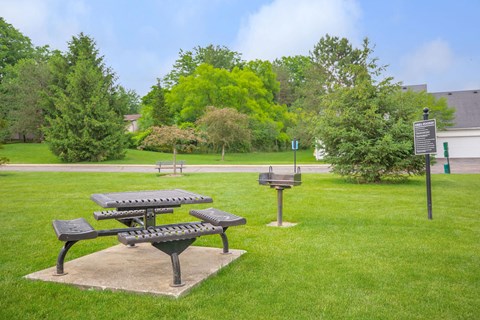 a park with picnic tables and a sign in the grass