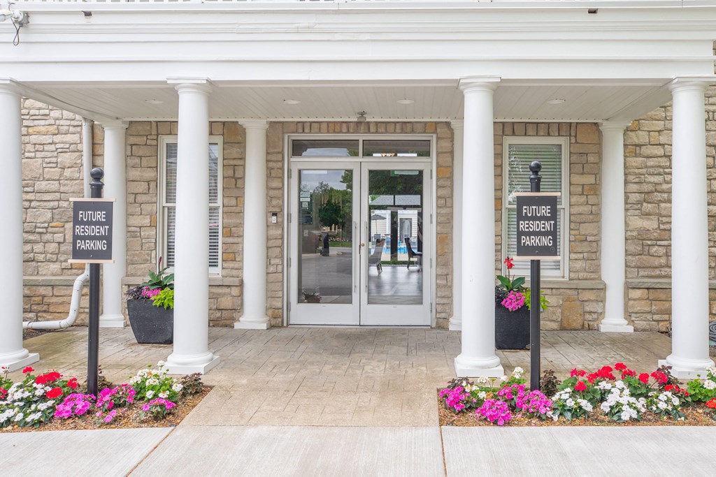 the front entrance of a building with white pillars and flowers