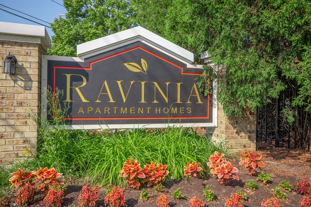 a sign apartment homes in front of trees and flowers