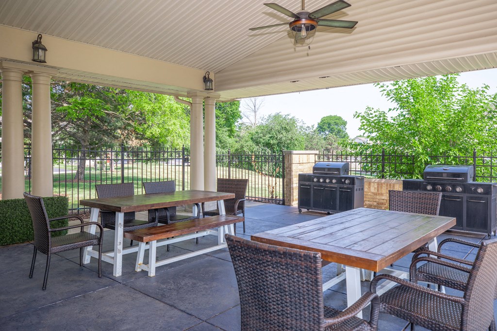 a covered patio with a table and chairs and a ceiling fan