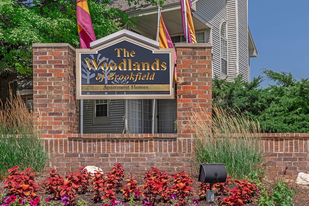 the woodlands at boroughsend sign on brick wall with flags
