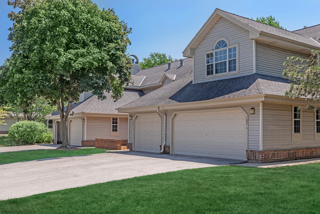 a white and tan house with a driveway and a tree