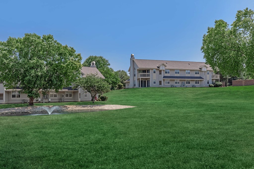 a large lawn with a fountain in front of a building