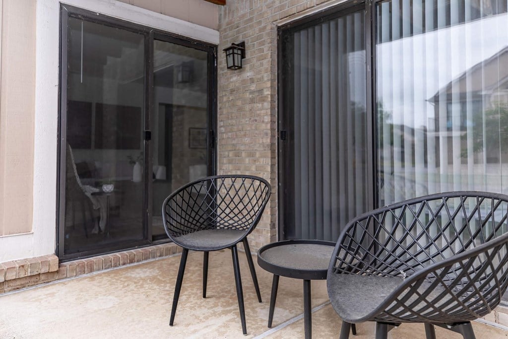 a patio with three chairs and a table on a balcony