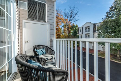 a balcony with two wicker chairs and a door to a building
