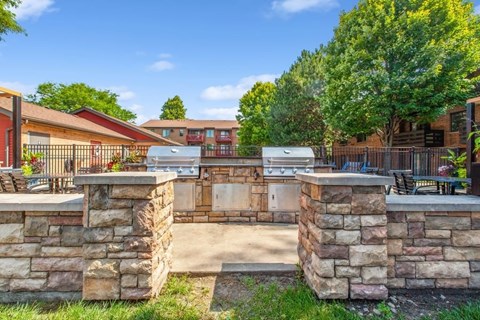 A stone wall with a gate in the middle and a building in the background.