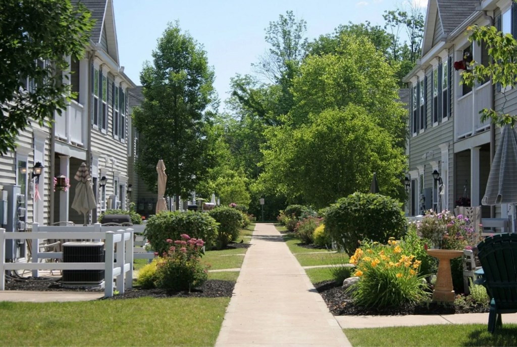 A residential street with houses on both sides and a sidewalk in the middle.