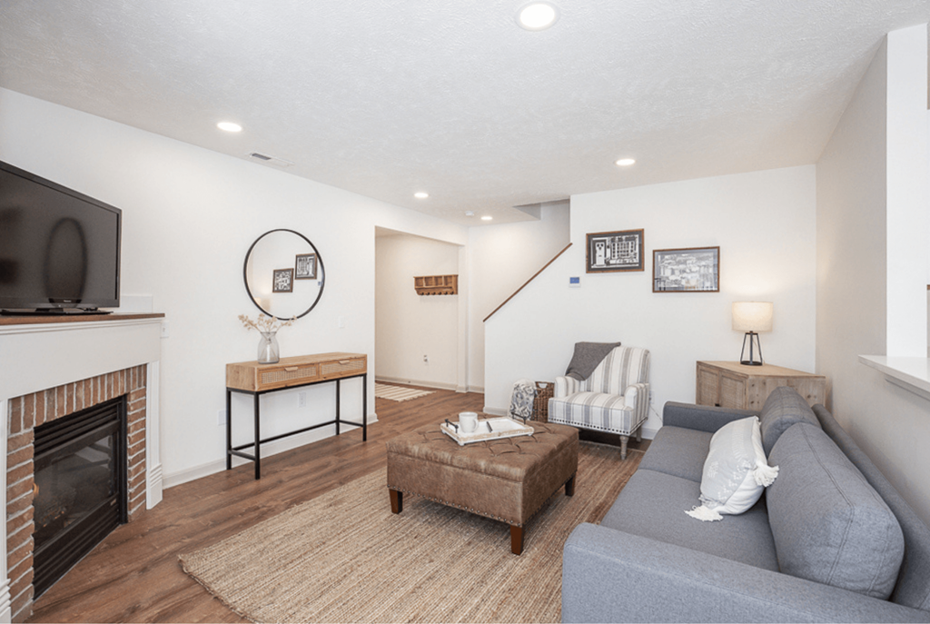 A living room with a grey couch and a fireplace.