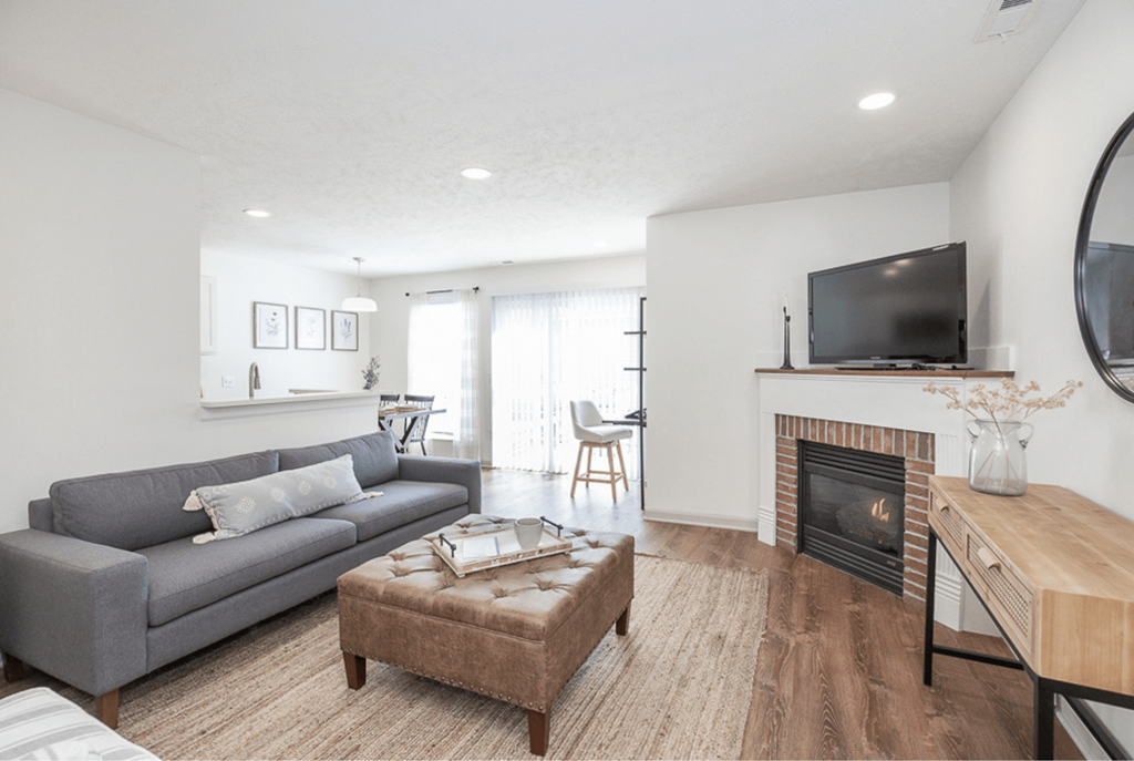 A living room with a grey couch, a fireplace, and a television.