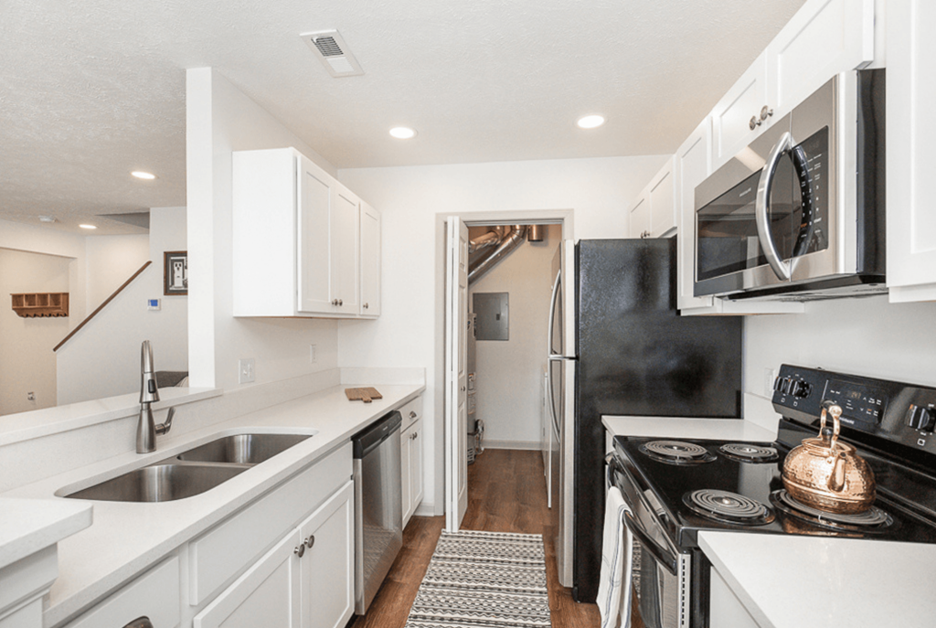 A kitchen with black appliances and white cabinets.