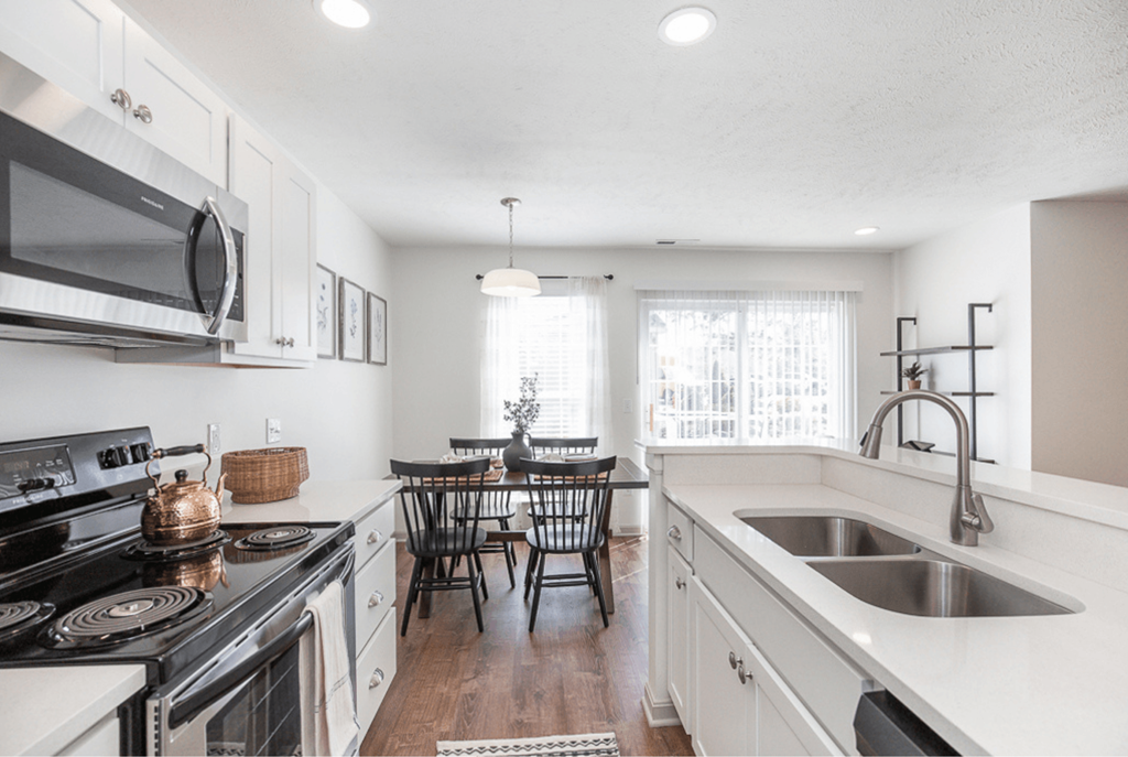 A modern kitchen with white cabinets and a wooden floor.