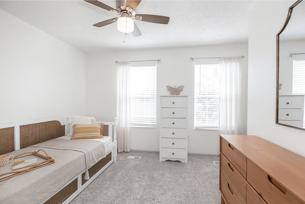 A bedroom with a bed, dresser, and mirror.