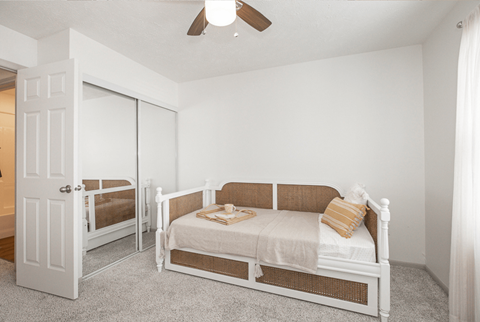 A white bedroom with a bed and a dresser.