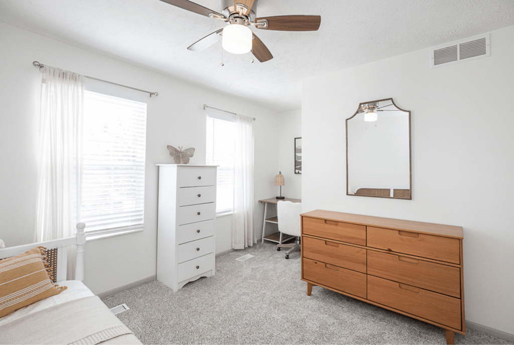 A bedroom with a white dresser and a wooden chest of drawers.