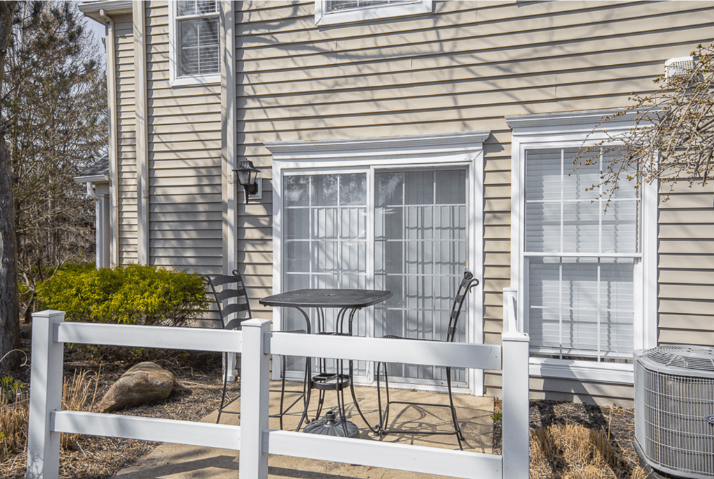 A house with a white fence and a table and chairs on the patio.