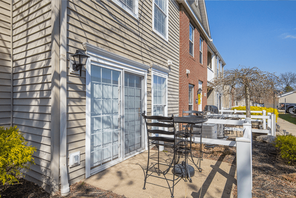 A patio with a table and chairs is in front of a house.