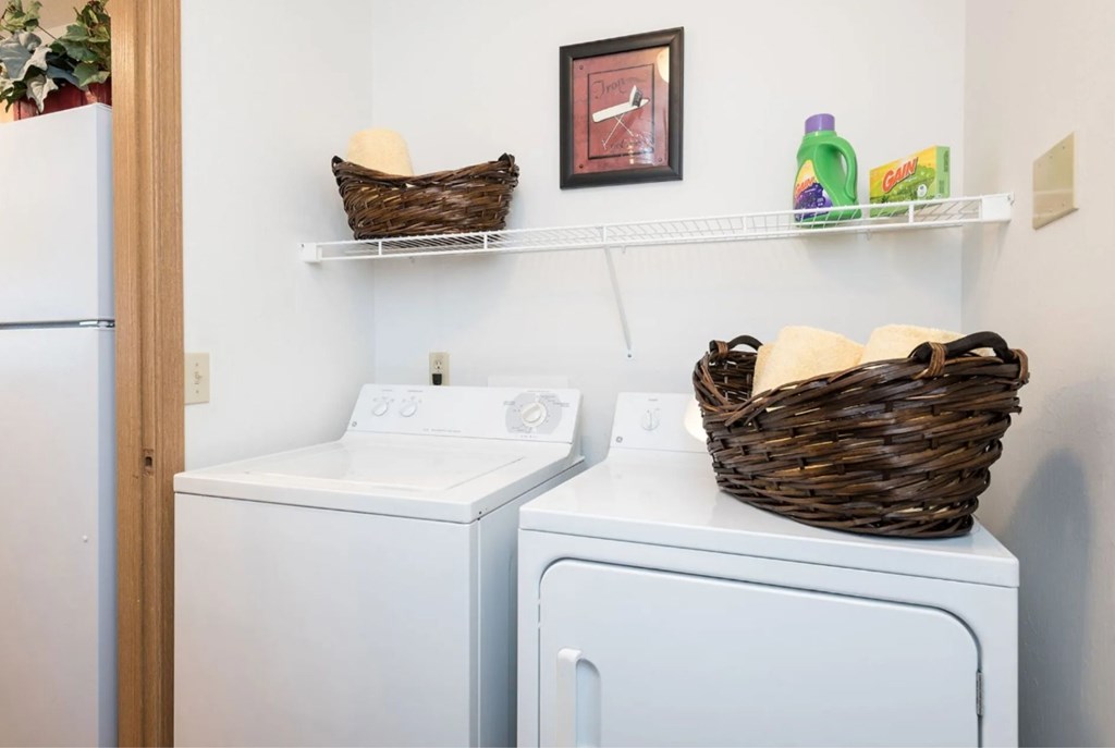 A laundry room with a washer and dryer and a basket on top of the dryer.