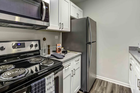 A black stove top oven with a digital display and a black refrigerator in a kitchen.