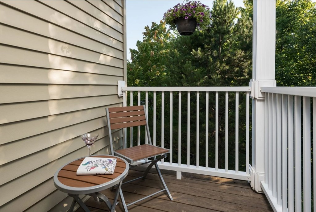 A small table with a glass and a cushion on it is on a deck.